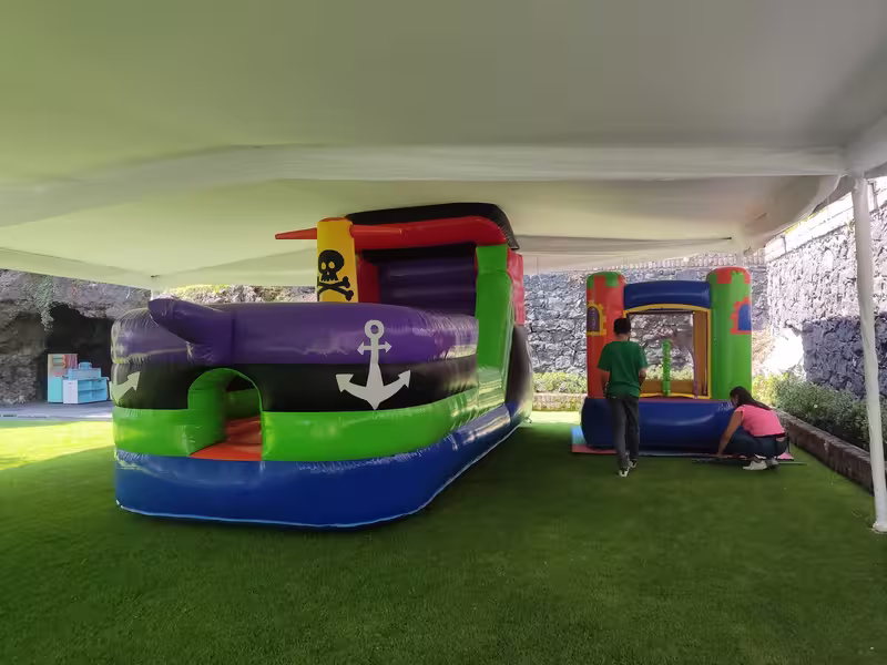 Castillo inflable de barco pirata instalado bajo carpa en exterior